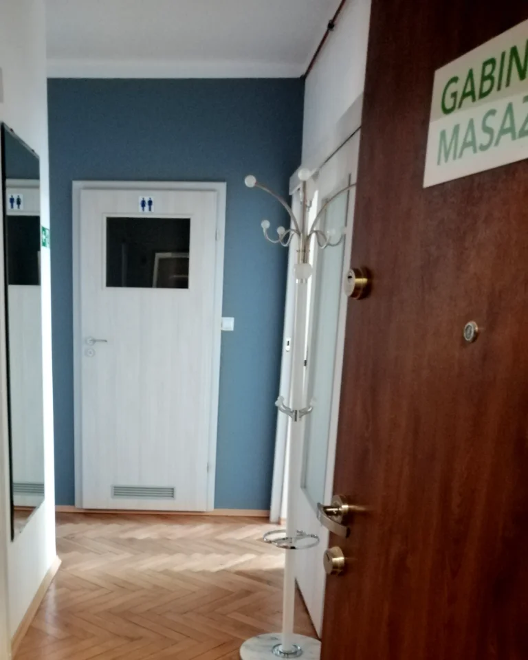 Wejście do gabinetu TULIKO: drzwi z tabliczką Gabinet masażu, korytarz z wieszakiem i toaletą